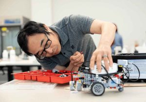 A teacher in the CCW course examines a robot